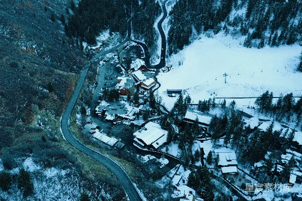 高清摄影 空中俯瞰一座被雪覆盖的山村，蜿蜒的小路蜿蜒其中。