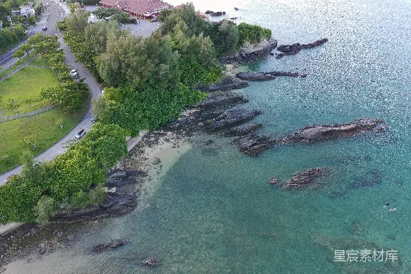 高清摄影 岩石海岸线，清澈湛蓝的海水和茂密的绿色植被。