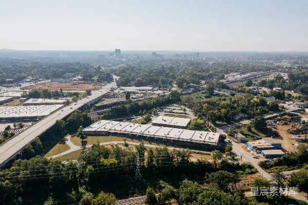 高清摄影 工业建筑和高速公路的俯瞰图，周围环绕着树木。