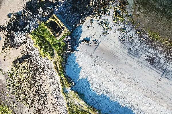 高清摄影 沙滩松软，海水清澈湛蓝，海岸岩石嶙峋，建筑废墟散落其中。