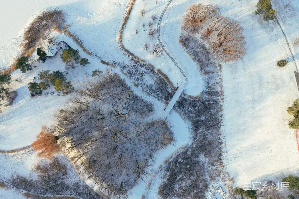 高清摄影 雪景中的公园，有蜿蜒的小路、树木和一座桥。