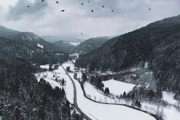 高清摄影 一座被雪覆盖的山，中间有一条路。