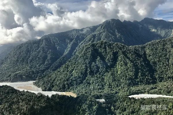 高清摄影 白天，一片云层覆盖的天空下，水边有一座青山。