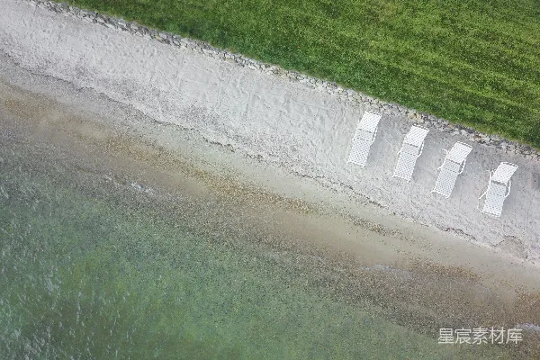 高清摄影 俯瞰四张白色躺椅在白色沙滩上的场景。