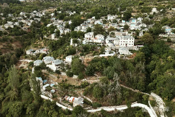 高清摄影 山坡上的村庄，有白色的建筑物和树木。