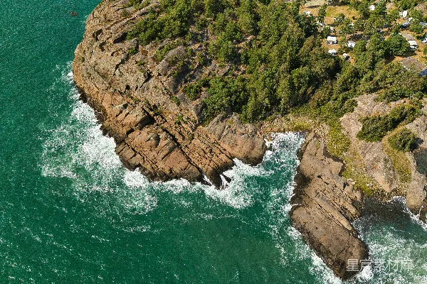高清摄影 岩石海岸线，绿树成荫，海浪拍打岸边。