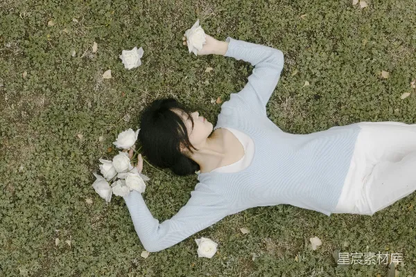 高清摄影 一个女人躺在草地上，手里拿着一束花。