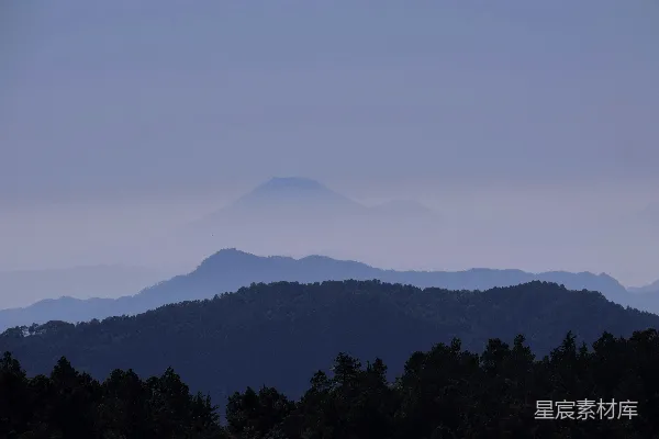 高清摄影 一座山脉的远景，前景中可以看到树木。