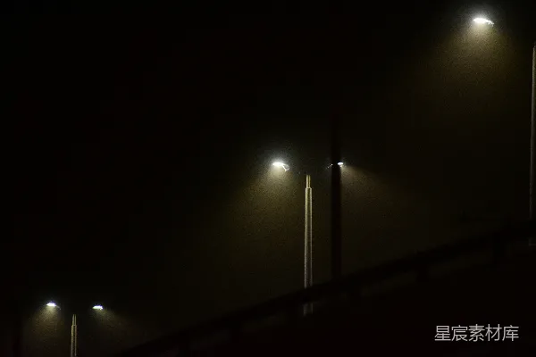 高清摄影 在一个雾蒙蒙的夜晚，一盏路灯在黑暗中亮着。