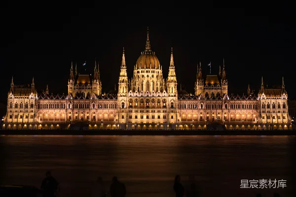 高清摄影 一座大型建筑物在夜间被照亮，旁边是一片水域。