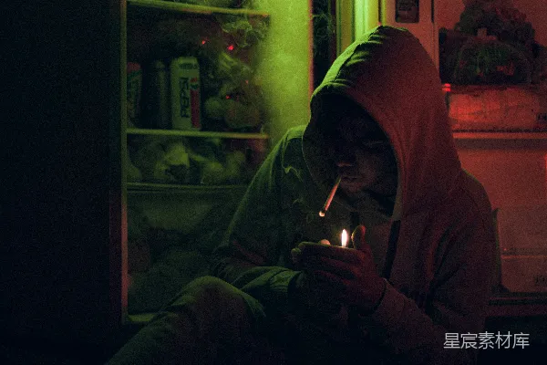 高清摄影 一个人坐在冰箱前，手里拿着一根点燃的蜡烛。