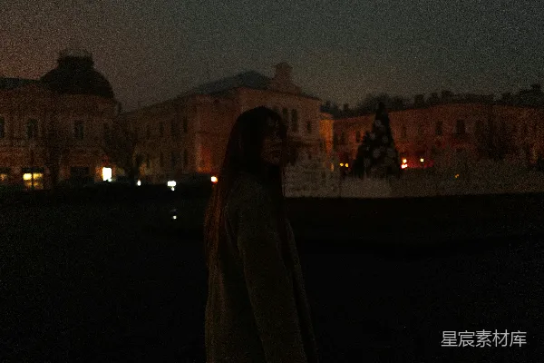 高清摄影 一个女人站在夜晚的建筑物前。
