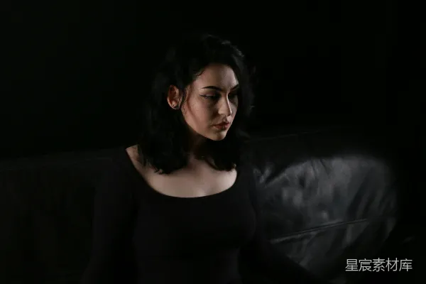 高清摄影 一个女人坐在黑色沙发的上面。