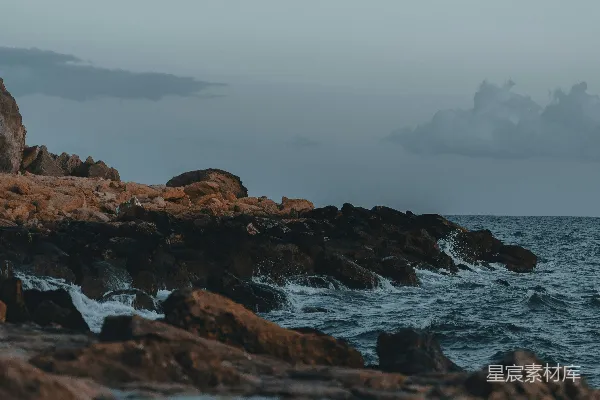 高清摄影 一个人站在岩石海岸边，面对着海洋。