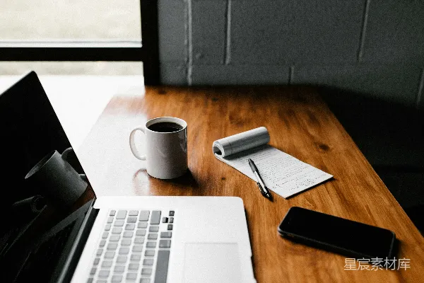 高清摄影 苹果MacBook Pro、白色陶瓷杯和黑色智能手机放在桌子上。