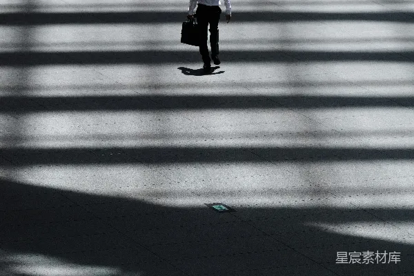 高清摄影 一个男人拿着笔记本电脑包走在街上。