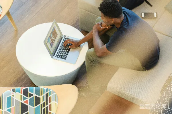 高清摄影 一个男人坐在沙发上使用MacBook。
