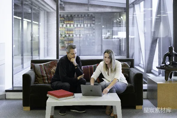 高清摄影 男人和女人坐在沙发上使用MacBook。