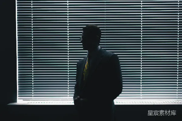 高清摄影 穿黑色西装的男人站在窗前的百叶窗旁边