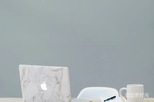高清摄影 桌子上的MacBook旁边有一个杯子。