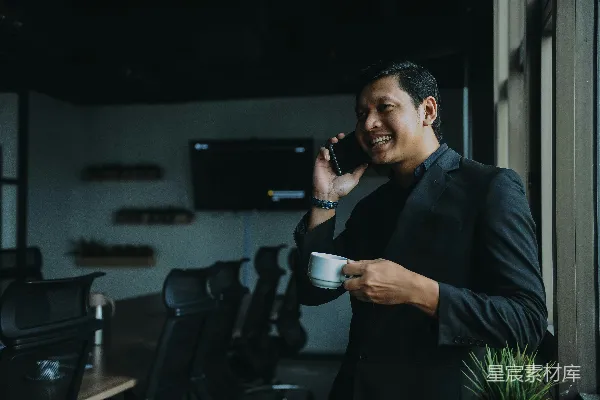 高清摄影 微笑的男人手里拿着杯子并使用智能手机。
