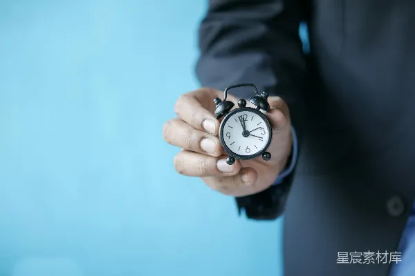 高清摄影 一个穿着西装的男人拿着一个小型闹钟