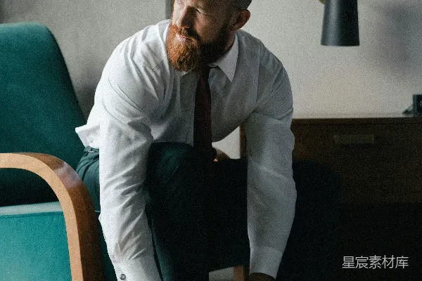 高清摄影 穿白色领带和黑色裤子的男人站在棕色木椅旁边。