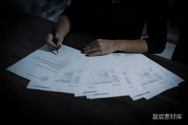 高清摄影 一位女士坐在桌子旁，桌上有很多文件。