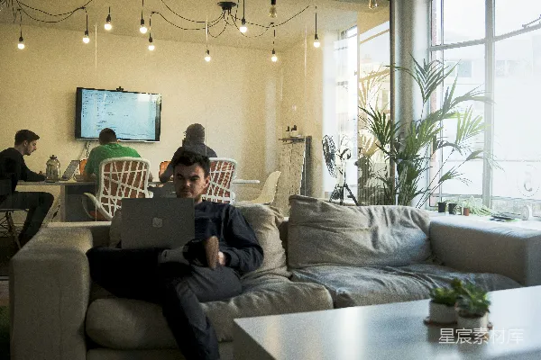 高清摄影 穿着黑色T恤的男人坐在沙发上使用MacBook电脑。