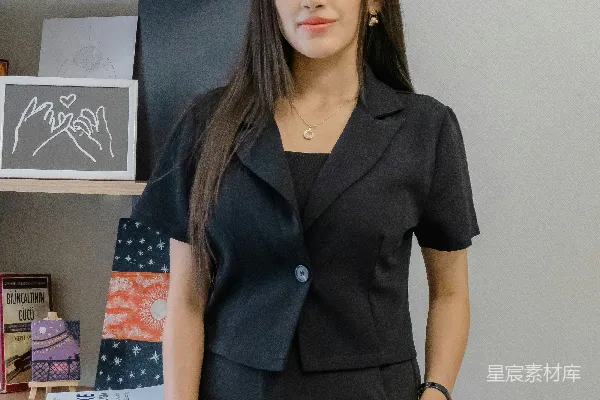 高清摄影 一位穿着黑色西装的女士站在书架旁。