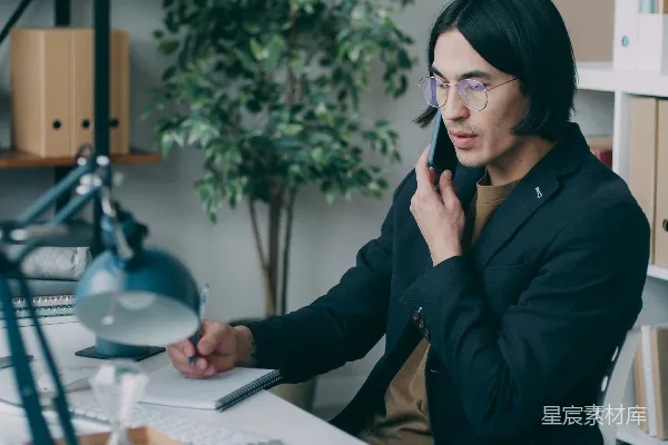 高清摄影 一个男人坐在桌子旁打电话。