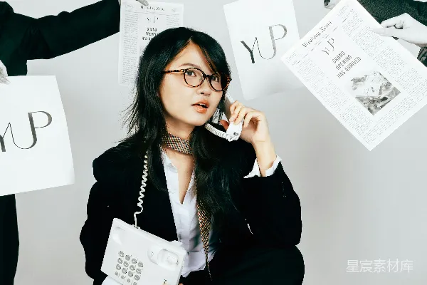 高清摄影 穿着西装的女士正在用老式电话通话，周围散布着文件。