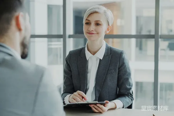 高清摄影 穿西装的女人在桌子对面采访一个男人。
