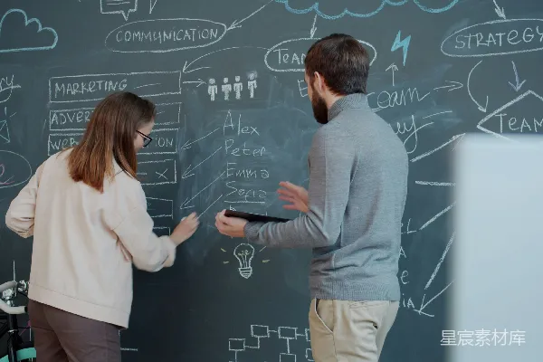 高清摄影 两个人在黑板上合作，画着图表。