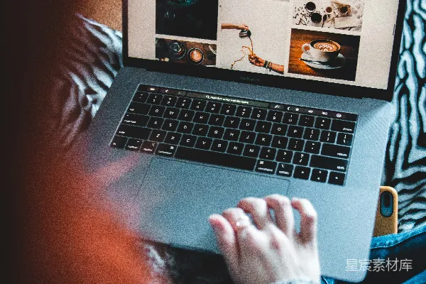高清摄影 使用MacBook Pro的人坐在黑白纺织品上。