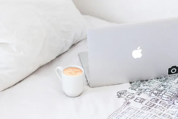 高清摄影 白色的陶瓷咖啡杯放在MacBook Air旁边。