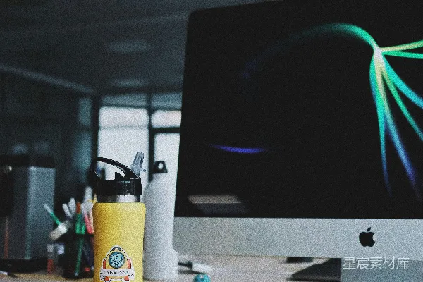 高清摄影 打开的银色iMac旁边放着一个黄色的杯子。