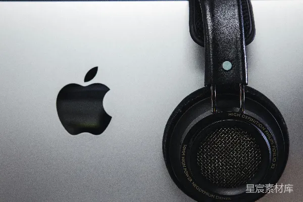 高清摄影 黑色和灰色耳机旁边有一台银色的iMac。