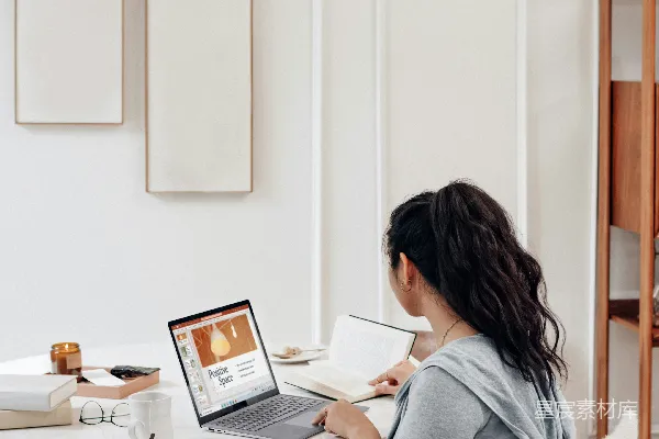 高清摄影 穿着灰色毛衣的女人正在白色的桌子上使用MacBook Air。