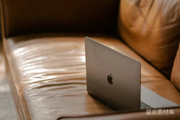 高清摄影 银色的MacBook放在棕色皮沙发上