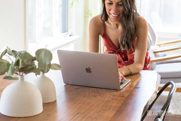 高清摄影 穿红色无袖上衣的女人坐在椅子上使用MacBook。