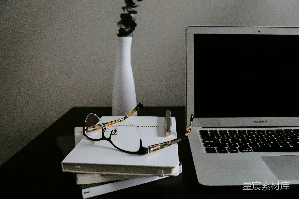 高清摄影 银色的MacBook Air放在黑色桌子上，旁边有一副眼镜。