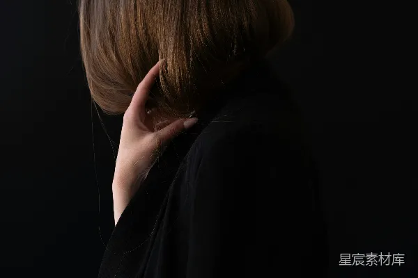 高清摄影 一个穿着黑色外套的女人正把一只手放在耳边。