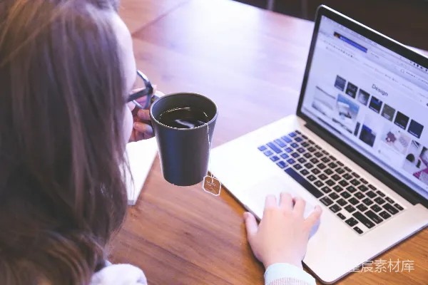 高清摄影 正在用MacBook的女性手里拿着装满茶的杯子。