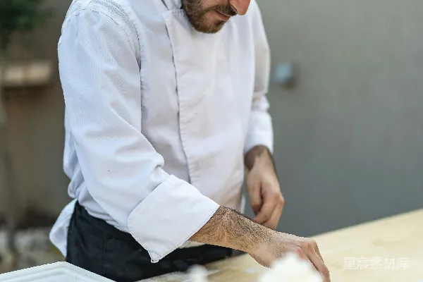 高清摄影 一个穿着厨师制服的人在桌子旁准备食物。