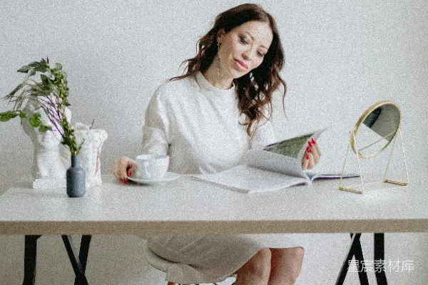 高清摄影 一个女人坐在桌前阅读一本书。