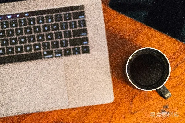 高清摄影 黑色陶瓷杯放在棕色木质表面上，旁边有一台MacBook Pro笔记本电脑。