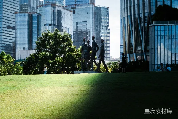 高清摄影 剪影般的身影在草地上走过，背景是摩天大楼。