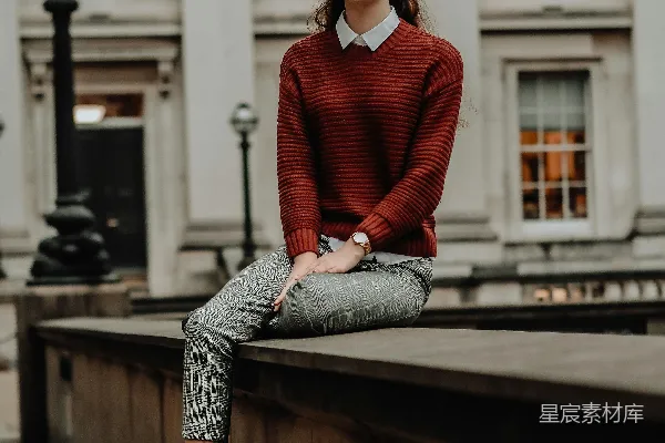 高清摄影 穿着红色毛衣和蓝色牛仔裤的女人坐在棕色木制长凳上，白天。