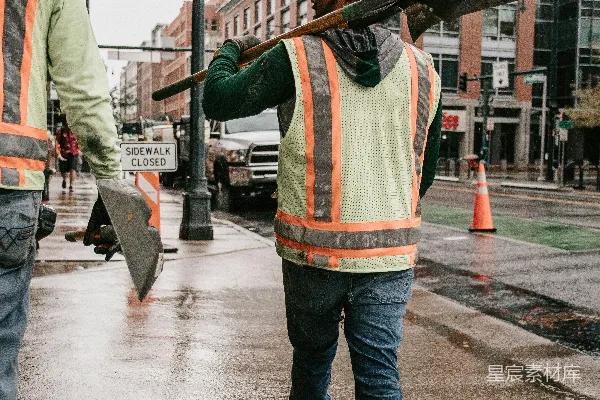 高清摄影 一个建筑工人扛着一个大铲子穿过一条湿漉漉的街道